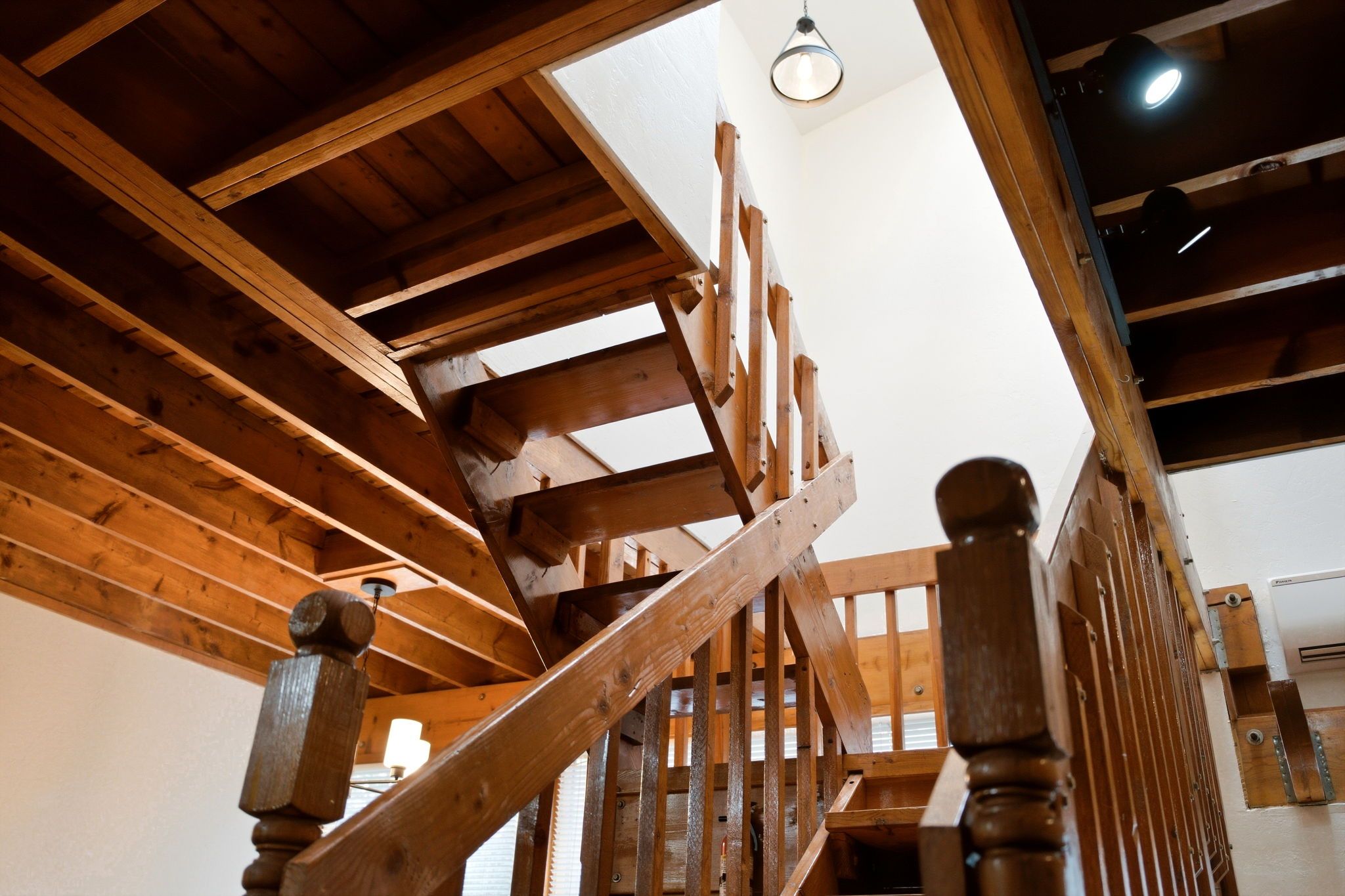 Una escalera de madera con barandilla y una lámpara en el techo.
