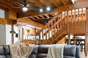 A wooden interior with a staircase, a leather sofa, and a kitchen area. - Premium Cabana - Outdoor Jacuzzi (Tijeras)