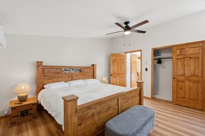 Een slaapkamer met een houten bed, een plafondventilator, een kledingkast en een bankje.