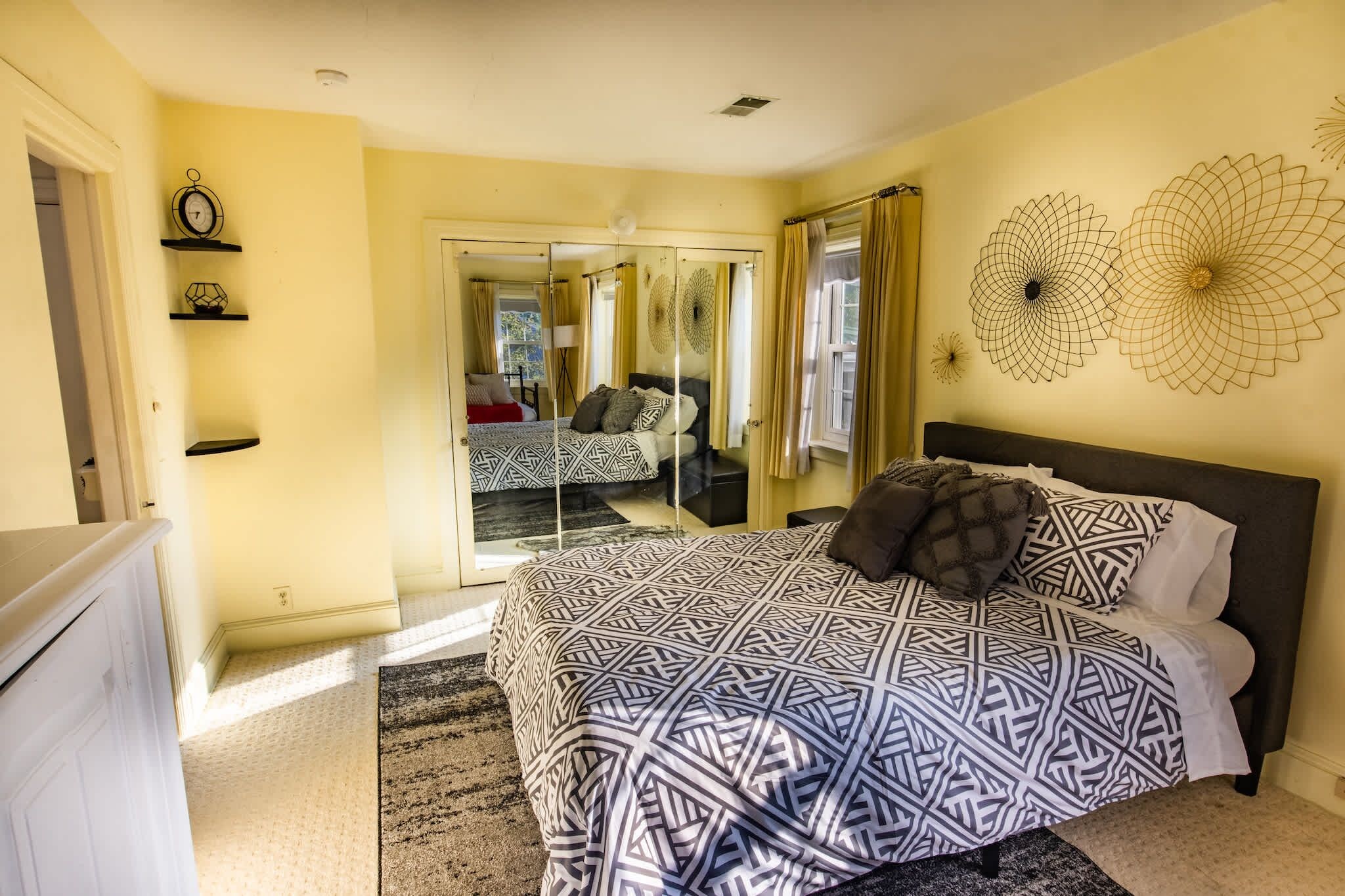 A bedroom with a large bed, a mirror, and a door leading to another room.