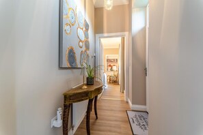 A hallway with a wooden console table, a potted plant, and a wall-mounted abstract painting. - 2 Bed in Winchburgh (oc-h44720) (Broxburn)
