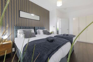 Ein modernes Schlafzimmer mit einem großen Bett, einem Nachttisch und einem Kleiderschrank.
