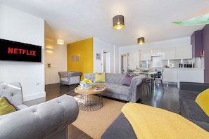Ein modernes Wohnzimmer mit einem grauen Sofa, einem Couchtisch und einem an der Wand montierten Fernseher.