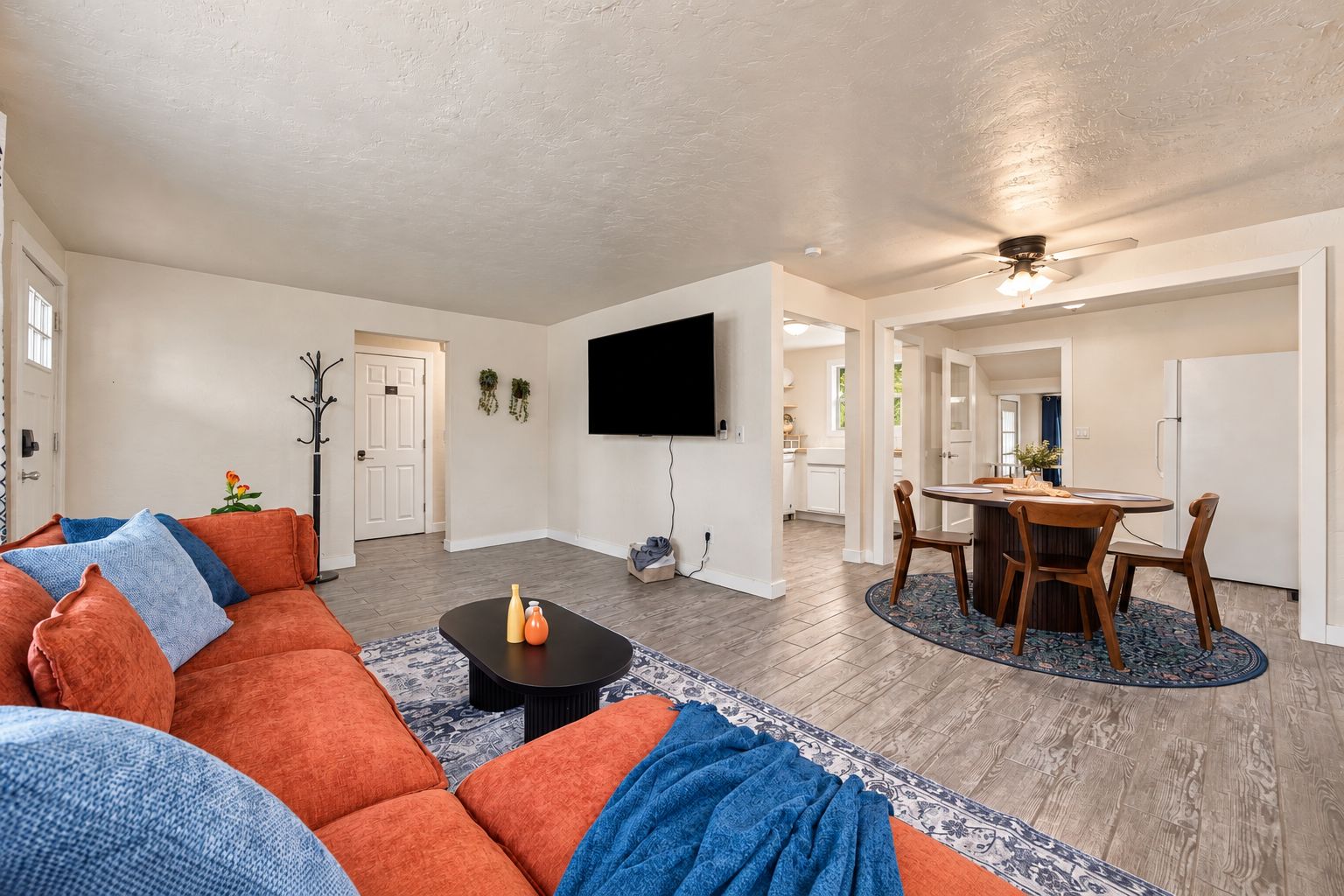 A spacious living room with a sofa, coffee table, and a dining area with chairs and a table.