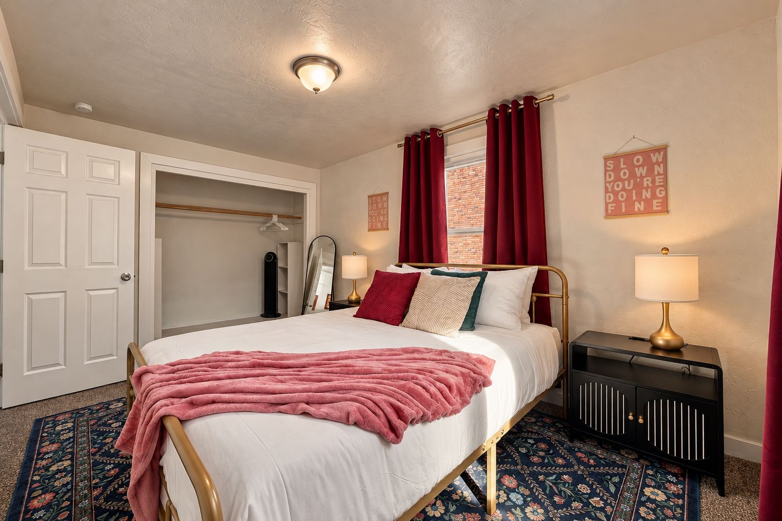 A hotel room with a bed, a bedside table with a lamp, a wardrobe, and a mirror.