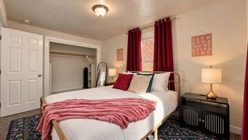 A hotel room with a bed, a bedside table with a lamp, a wardrobe, and a mirror.