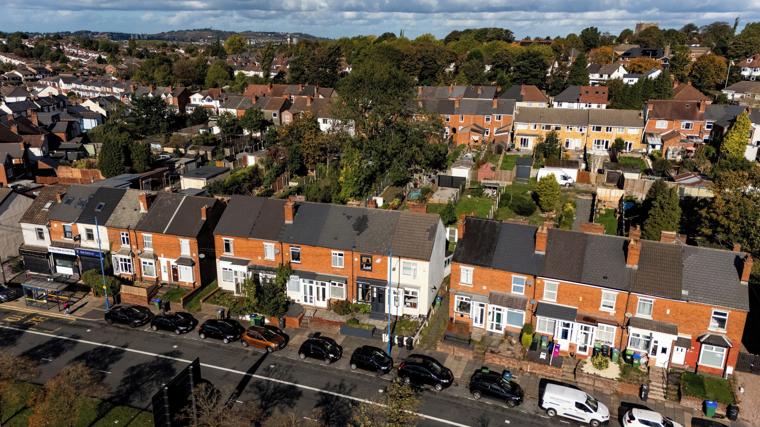 A residential area with terraced houses, a main road, parked cars, and a visible business establishment.