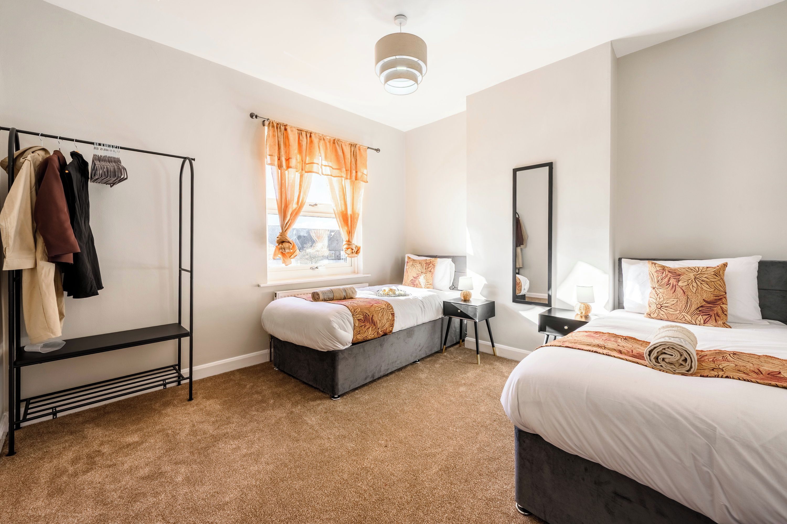 A hotel room with a bed, a desk, a wardrobe, and a window with curtains.