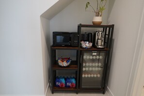 Pieni keittiönurkkaus, jossa on mikroaaltouuni, kahvinkeitin ja jääkaappi.