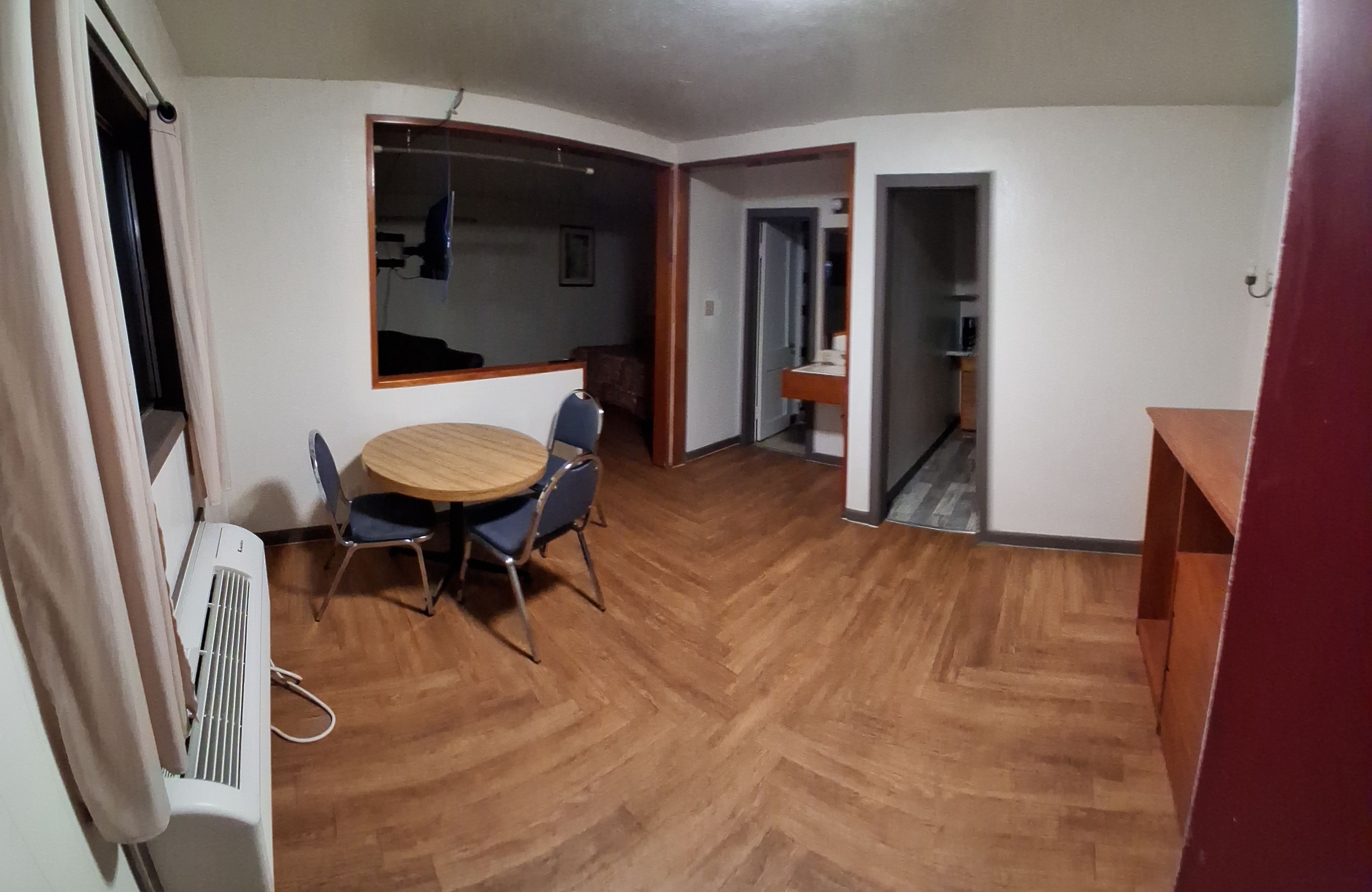 Una habitación con una mesa de comedor, sillas, un radiador y suelo de madera.