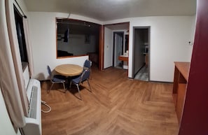Una habitación con una mesa de comedor, sillas, un radiador y suelo de madera.