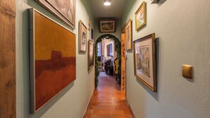 A hallway with artwork on the walls, a wooden door, and a tiled floor. - 17th-century Chapel Smart Home in Historic Sintra (Sintra)