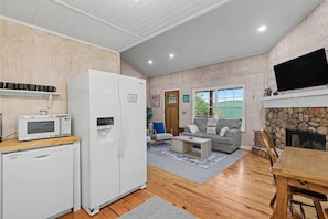 A modern kitchen with a microwave, refrigerator, and dishwasher. There is a seating area with a sofa and a fireplace.