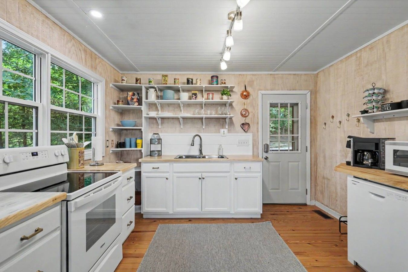 A kitchen with white cabinetry, a built-in oven, a microwave, and a coffee maker on the countertop.