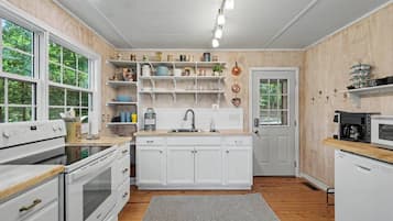 A kitchen with white cabinetry, a built-in oven, a microwave, and a coffee maker on the countertop.