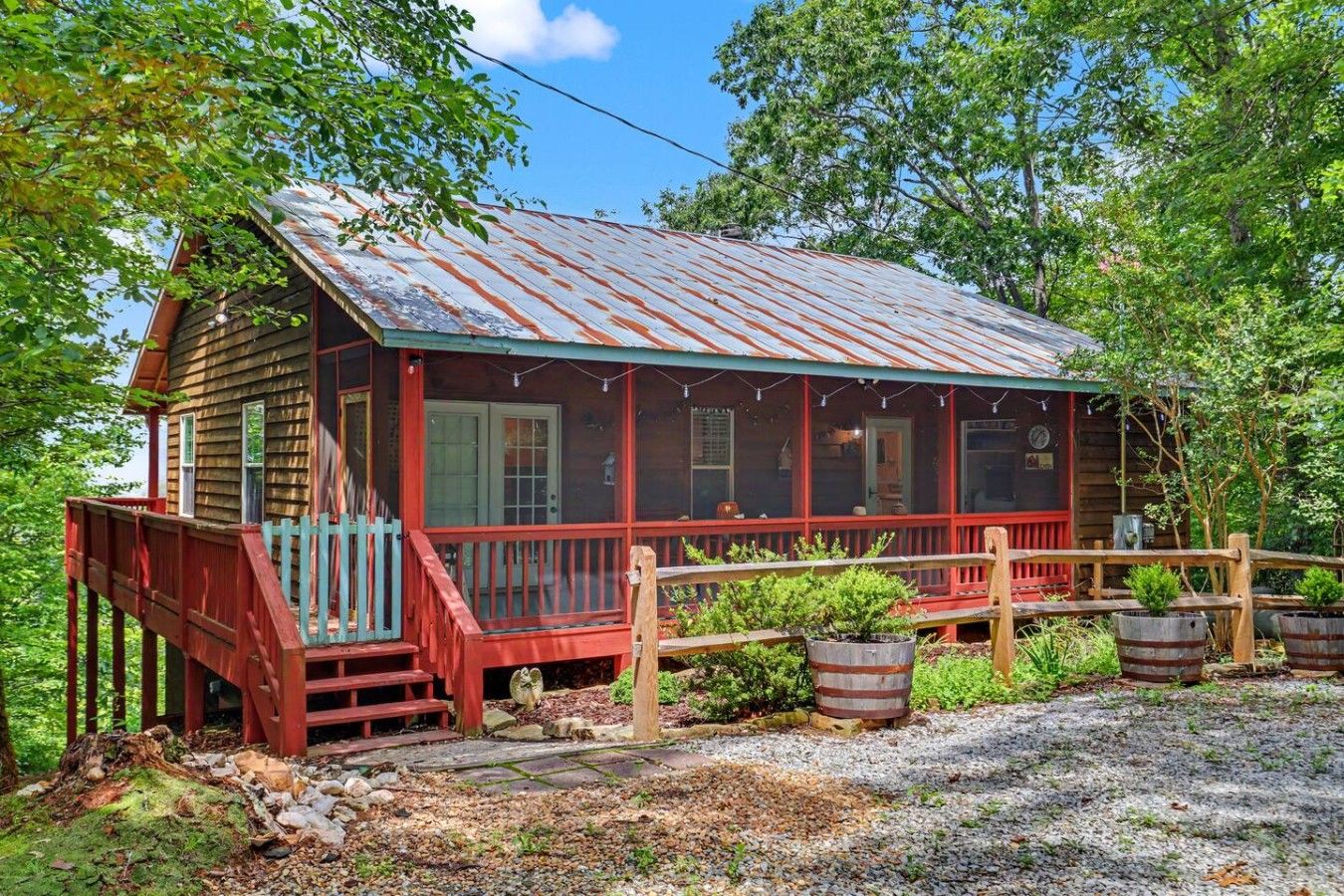 A rustic cabin with a porch, surrounded by trees.