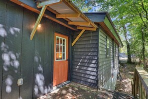 Eine Holzhütte mit roter Tür, einer kleinen Veranda und einem Fenster.