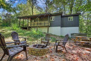 Eine Hütte mit einer Terrasse, Sitzgelegenheiten im Freien und einer Feuerstelle.