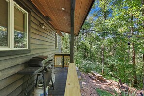 Eine Holzhütte mit überdachter Veranda, Grill und Picknicktischen.