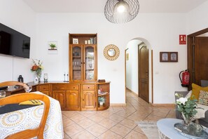 A well-lit living room with a dining area, wooden cabinets, a television, and a fire extinguisher. - TenoHomes La Perla Natural Pools Garachico (Garachico)