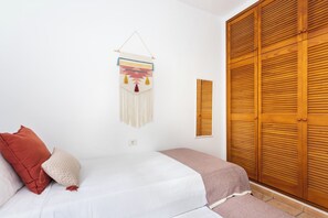 Un dormitorio con cama, un adorno en la pared y un armario de madera.
