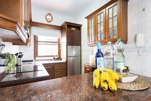 A kitchen with granite countertops, wooden cabinets, a stainless steel refrigerator, and a window with a view. - TenoHomes La Perla Natural Pools Garachico (Garachico)