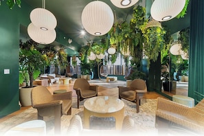 A modern lounge area with wicker furniture, hanging plants, and unique lighting fixtures.