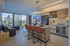 A modern kitchen with a central island, bar stools, and a dining area with a sofa and coffee table. - New Listing (Guadalajara)