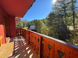 A wooden balcony with heart-shaped cutouts, overlooking a forested area with mountains in the background. - T4 spacieux avec grand balcon – 6 pers aux Balcons de Sirius Risoul (Risoul)