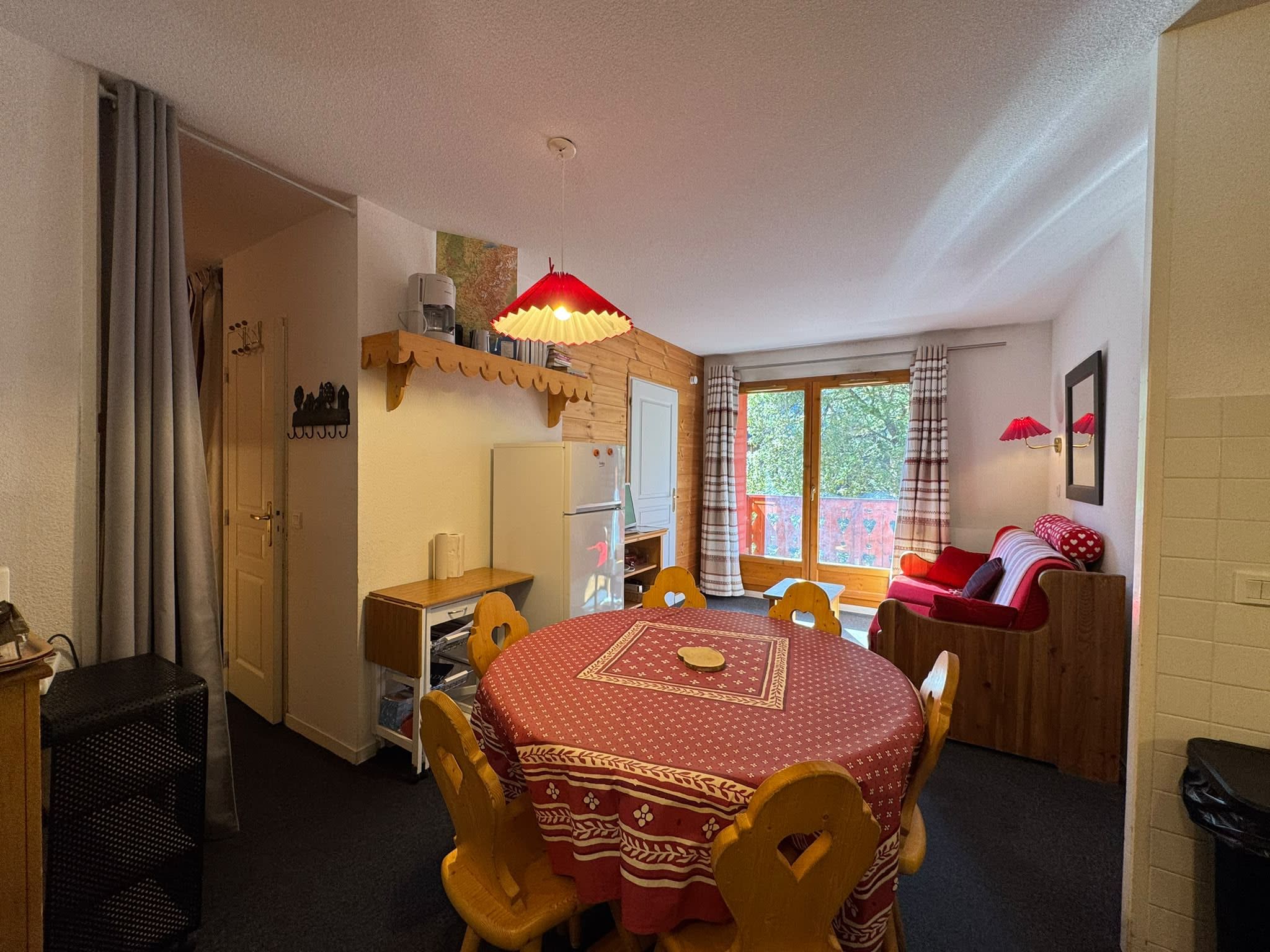 Une pièce chaleureuse comprenant une table à manger, des chaises, un canapé et une fenêtre avec des rideaux.