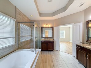 Ein modernes Badezimmer mit einer großzügigen Badewanne, einer Duschkabine aus Glas und einem Waschtisch mit Spiegel.