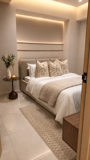 A modern bedroom with a bed, bedside table, and a nightstand. - Luxury Apt / Pool / Steps to BlueMall (Santo Domingo)