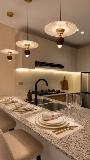 A modern kitchen with a central island, stainless steel appliances, and pendant lighting. - Luxury Apt / Pool / Steps to BlueMall (Santo Domingo)
