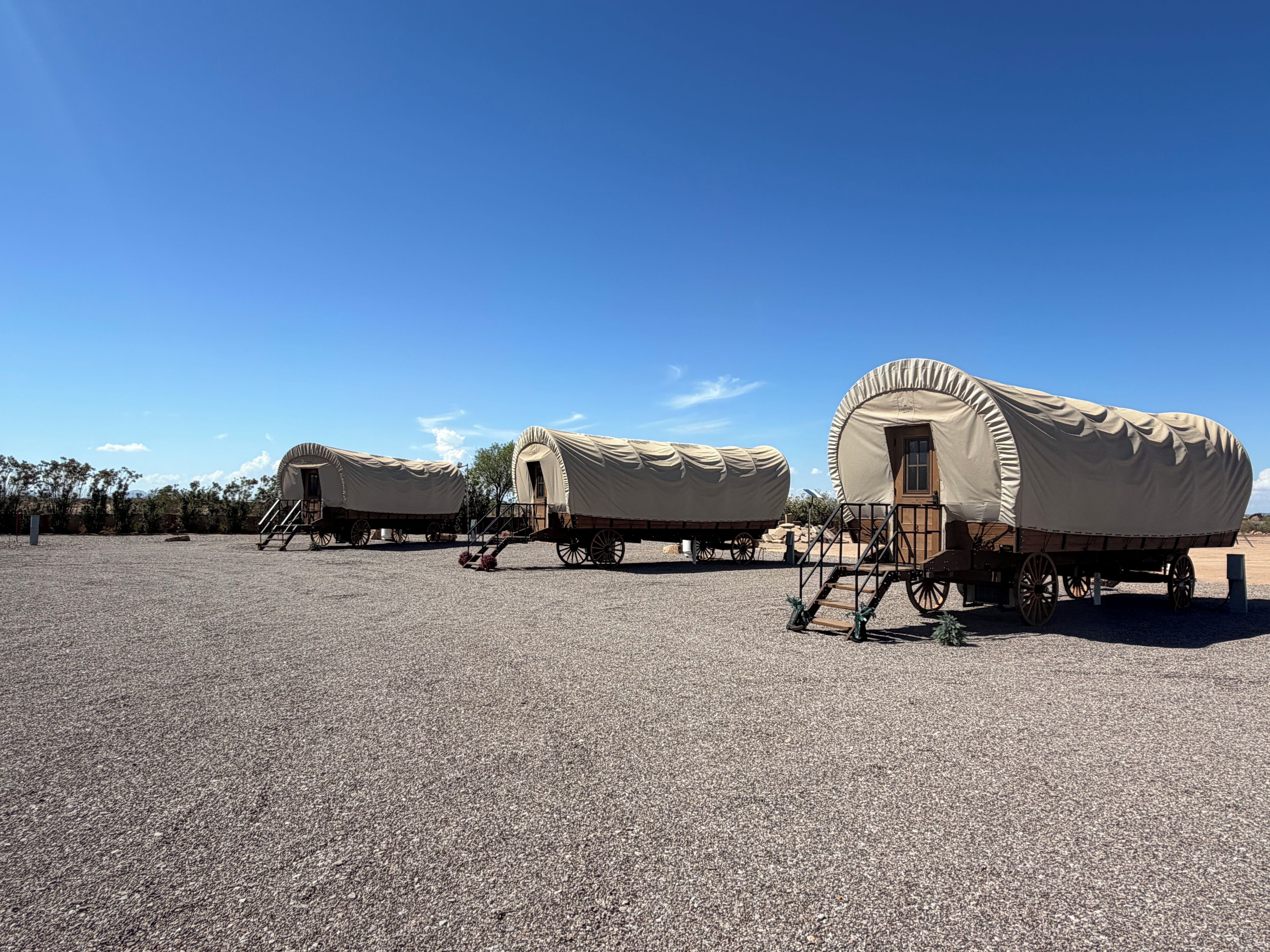 A series of covered wagons with steps leading up to the entrance, set on a gravel surface.
