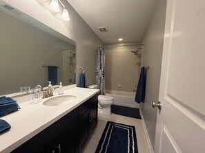 Un bagno con doppio lavabo, WC, doccia e un ampio specchio.