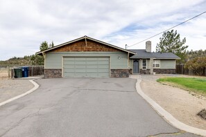 Ein eingeschossiges Gebäude mit Garage, Stein Fundament und umzäunter Garten.