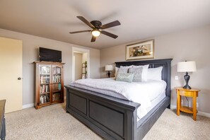 Ein Schlafzimmer mit Bett, Deckenventilator, Bücherregal, Nachttisch und Lampe.