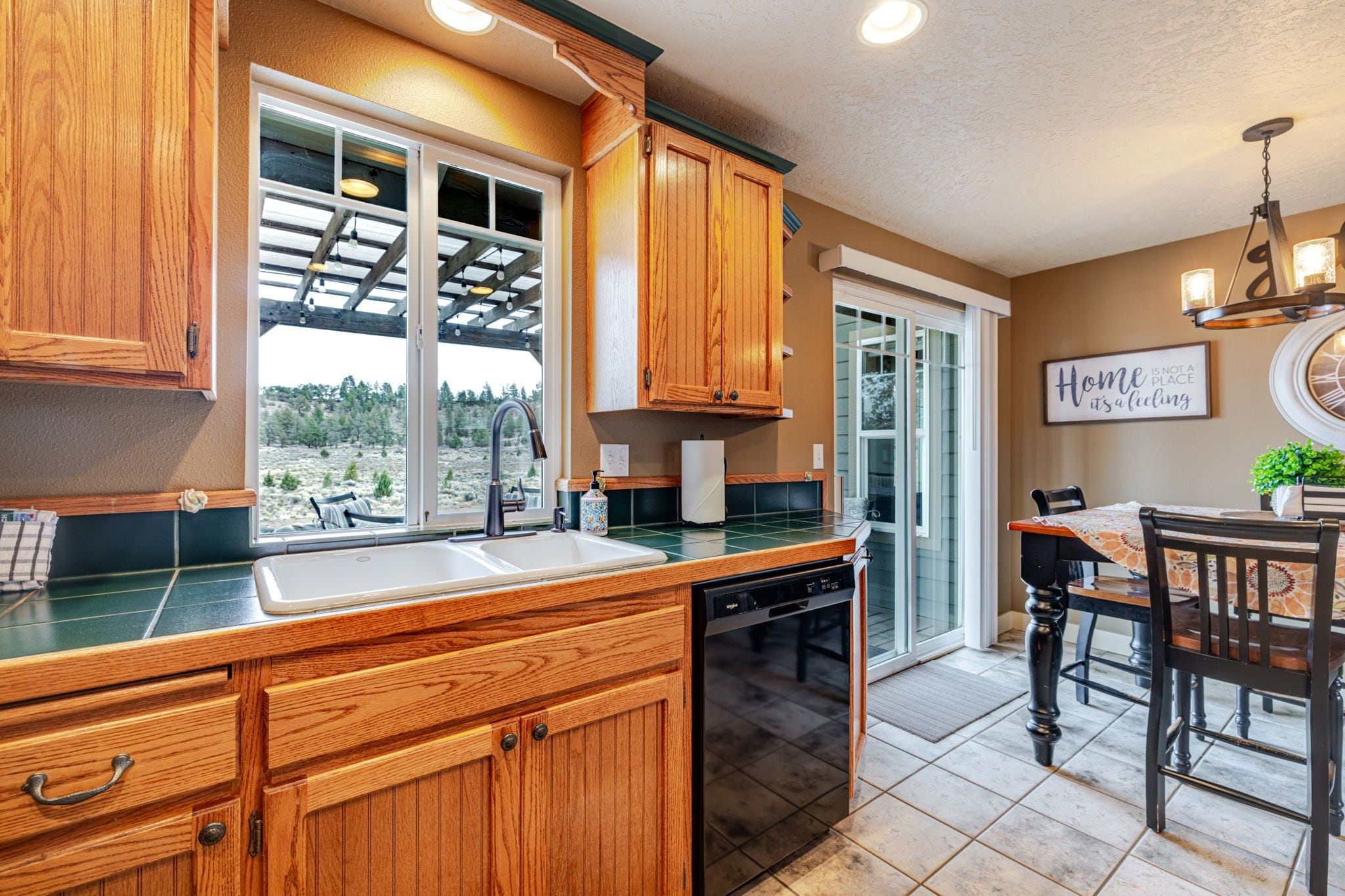 A kitchen with wooden cabinets, a dishwasher, and a window overlooking a landscape.