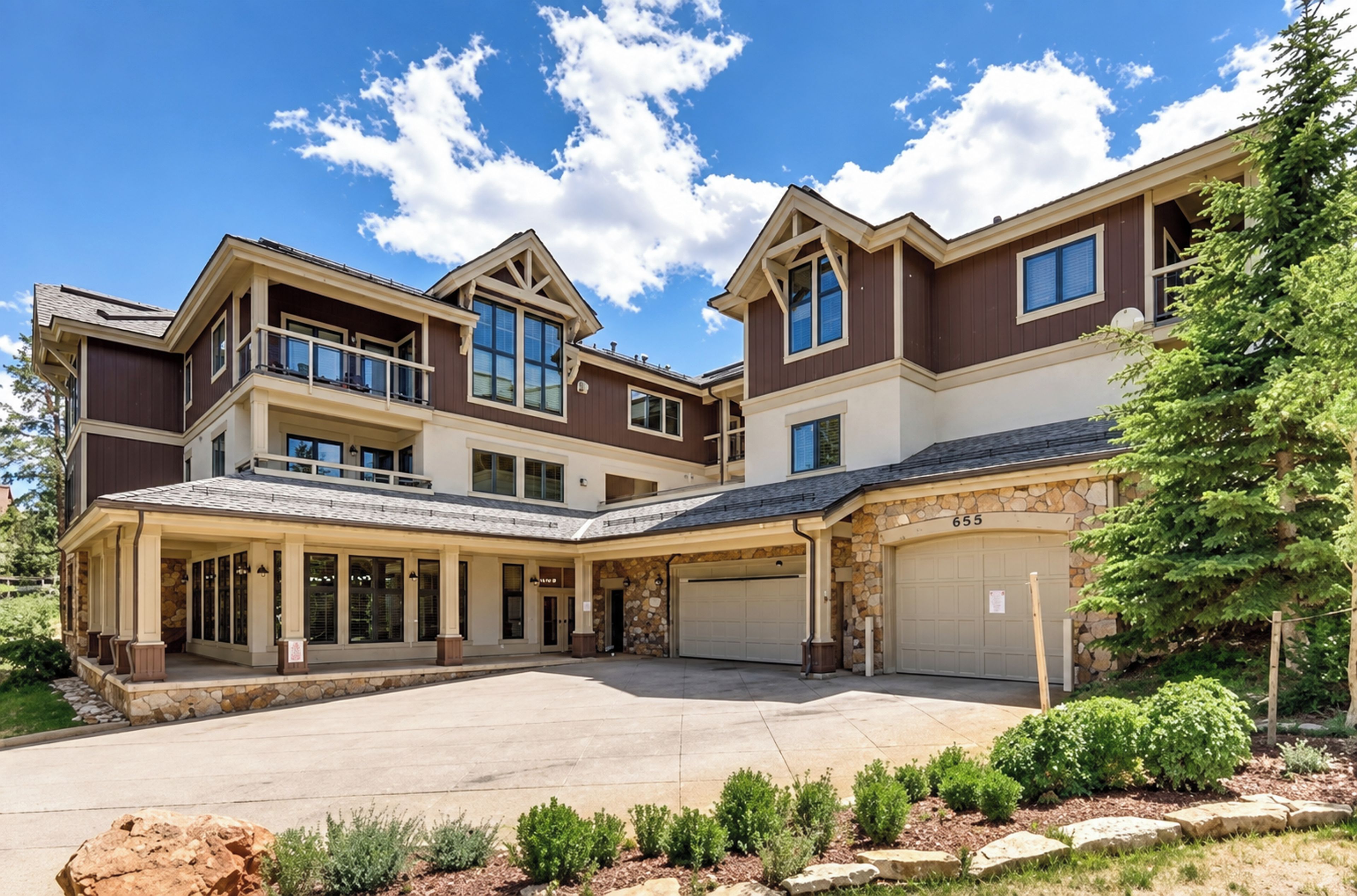 A two-story house with a covered front porch, a stone facade, and a garage.