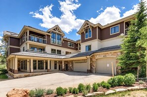 A two-story house with a covered front porch, a stone facade, and a garage. - Studio on Snowflake unit 204 (Breckenridge)