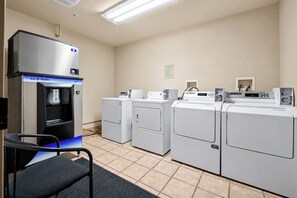 A laundry facility with a water dispenser, multiple washing machines, and a chair. - Studio on Snowflake unit 204 (Breckenridge)