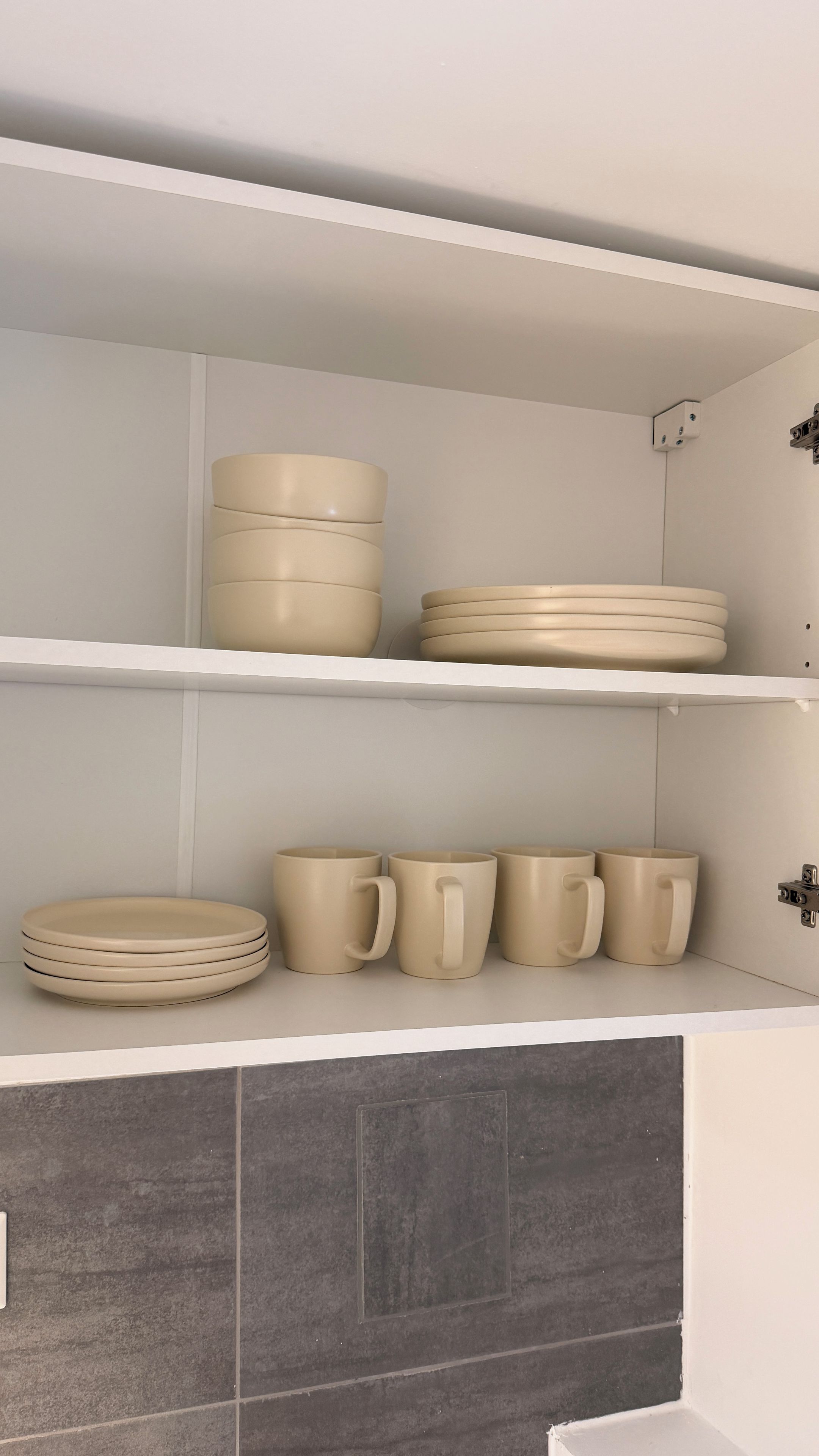 Uma cozinha com armários brancos e azulejos cinzas.