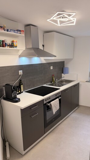 A modern kitchen with a built-in oven, a stovetop, and a range hood. - New Listing (Reutlingen)