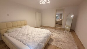 A bedroom with a bed, a wardrobe, a mirror, and a door leading to another room. - New Listing (Reutlingen)