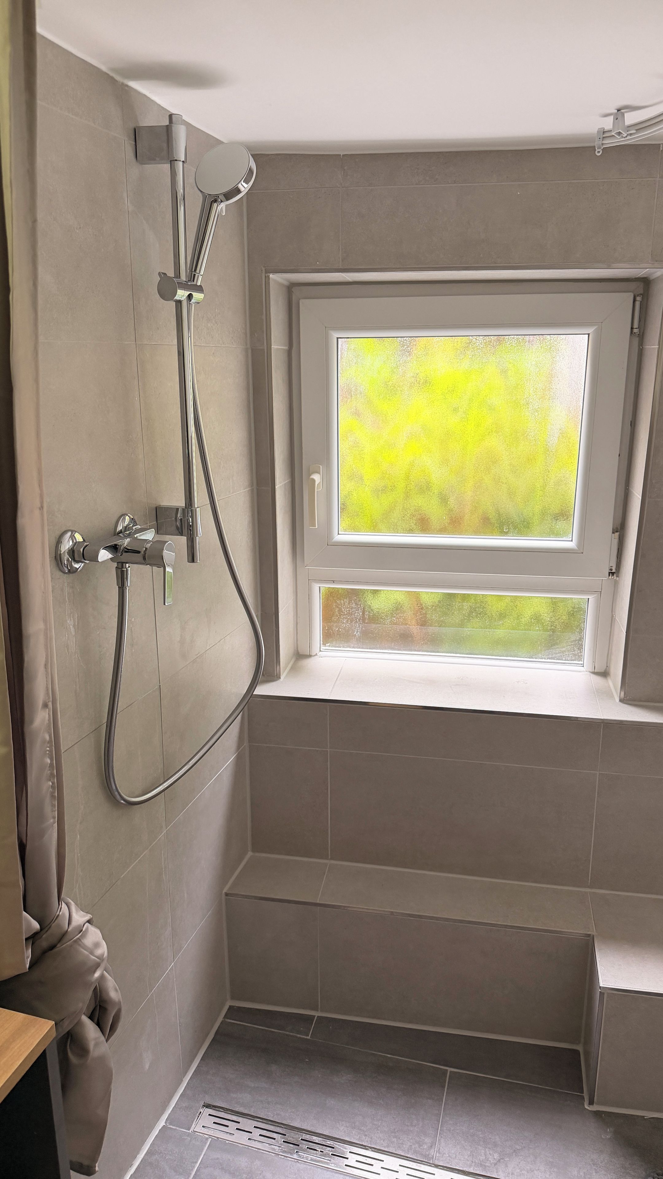 Ein Badezimmer mit Dusche, Fenster und Handtuchhalter.