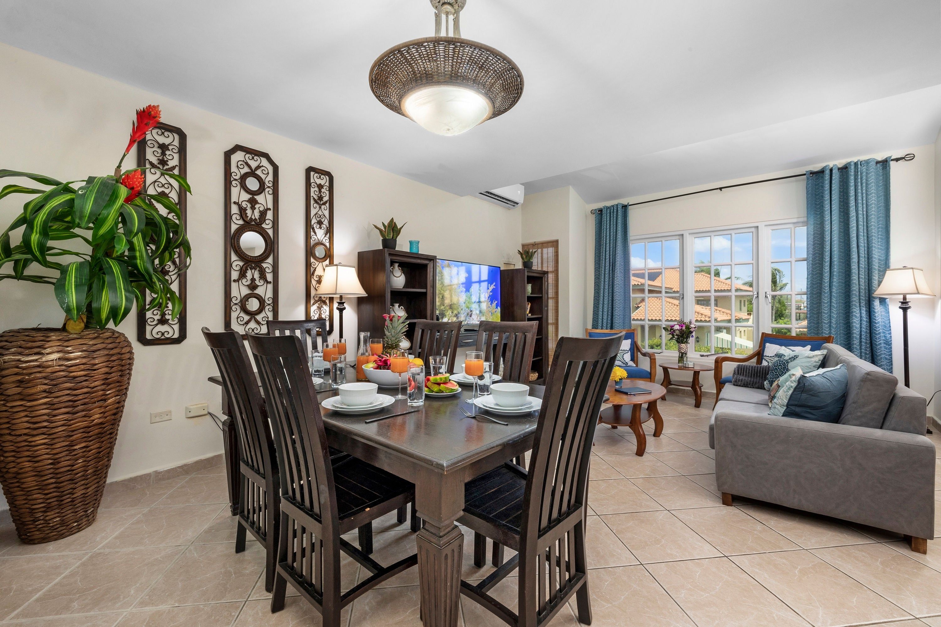 A dining area with a table set for four, surrounded by chairs, and a living room with a sofa and a TV.