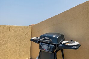 A barbecue grill with two plates attached, positioned against a textured wall. - Palma Real 29 - your vacation Condo in Palm Beach (Palma Real)