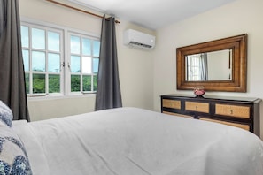 A bedroom with a bed, a dresser, a mirror, and a window with curtains. - Palma Real 29 - your vacation Condo in Palm Beach (Palma Real)