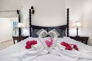 A neatly made bed with a towel arrangement in the center, two bedside tables with lamps, and a window with curtains. - Palma Real 29 - your vacation Condo in Palm Beach (Palma Real)