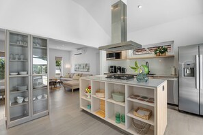 A modern kitchen with a central island, built-in appliances, and a dining area with a view. - Modern Three Bedroom Villa in Noord (Boegoeroei)
